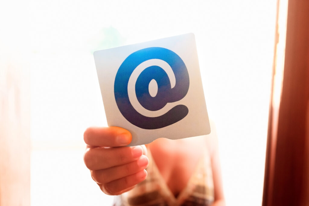 Person holding the at symbol between his fingers